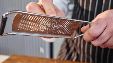 Close-up of a chef grating pecans with a metal grater. Slow motion 50fps. Stock Footage 308020965