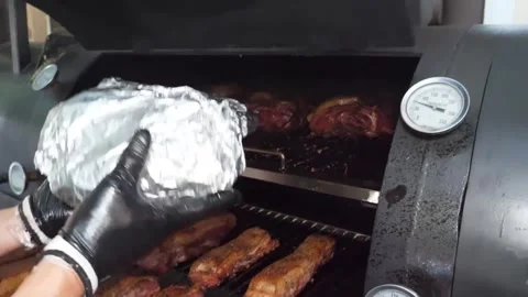 Close-up of a Chef Grilling Juicy Beef Steaks and Placing Foil-Wrapped Meat in a Видео 338212651