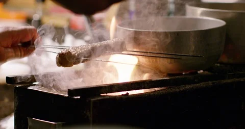 Close up of chef grilling meat on skewer in slow motion, Japan Stock Footage 124678939