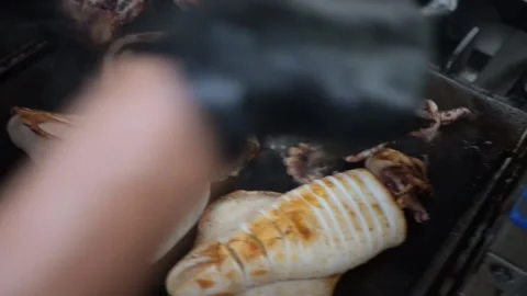 Close up of a chef grilling squid and meat on a commercial griddle Stock-Footage 323792375