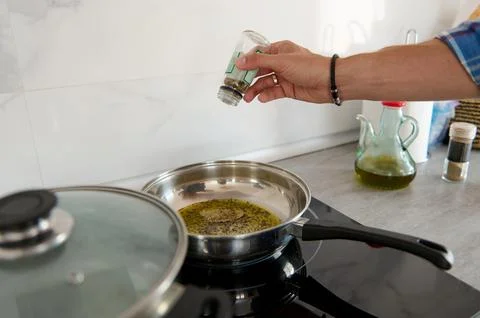 Close-up of chef hand adding pepper into a frying pan with bay leaf and vir.. Stock Photos