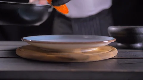 Close up of chef hand holding hot pan and adding salt to it with other hand Stock Footage 127046949
