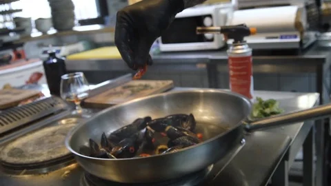 Close up chef hand puts chopped peppers in mussels fried in a pan Stock Footage 105272018