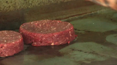 Close up of chef hands adding raw burgers on a griddle Stock Footage 127716068