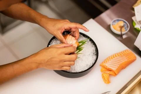 Close up of Chef Hands Plating Fresh Salmon Sashimi on Ice in Black Bowl Stock Photos