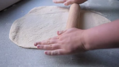 Close-up chef hands rolling out a dough with a wooden rolling pin Stock Footage 130656717