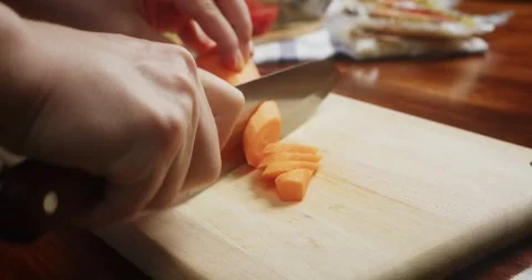 Close up of chef hands slicing fresh carrots on a wooden cutting board with a 스톡 동영상 337911175