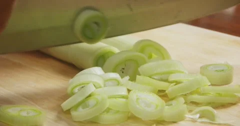 Close up of chef hands slicing fresh leek into thin rings on a wooden cutting Vidéo 337911705