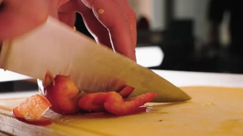 Close-up of chef hands slicing a red bell pepper on cutting board in a Stock Footage 302976521
