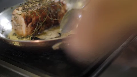 Close up. Chef hands in white uniform pour butter on meatloaf in a frying pan Stock Footage 88673294