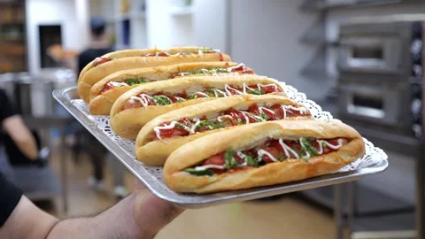 Close-up of a chef holding a tray of fresh hot dogs in a restaurant kitchen. Stock Footage 318139229