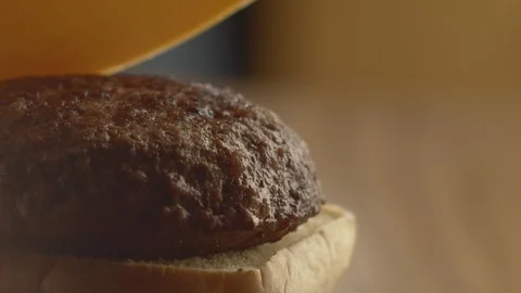 Close-up of chef in kitchen preparing hamburger and adding slice of cheese to Stock Footage 116036003