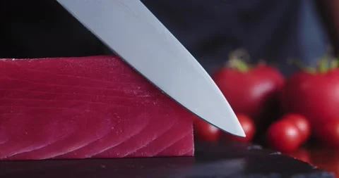 Close-up of chef in the kitchen touches fresh piece of raw tuna with sharp knife Stock Footage 148765848
