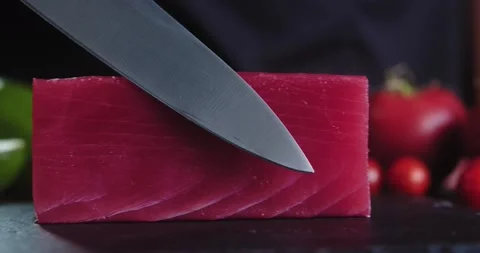 Close-up of chef in the kitchen touches fresh piece of raw tuna with sharp knife Stock Footage 148765937