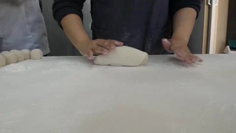 Close-Up of Chef Kneading and Shaping Dough on a Floured Surface 스톡 동영상 345291931
