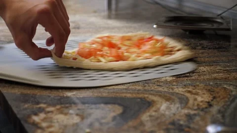 Close-up of a chef lifting a pizza with a long-handled spatula in a pizzeria. Stock Footage 307388798