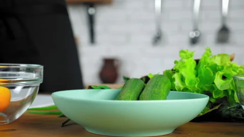 Close up chef man hands put fresh food cucumbers in plate at home kitchen Stock Footage 149745569