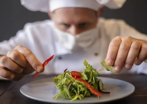 Close up chef with mask preparing dish. High quality photo Stock Photos