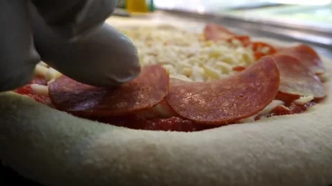 Close-up of Chef Placing Pepperoni Slices on Fresh Italian Pizza Dough Before Ba Stock Footage 337676792