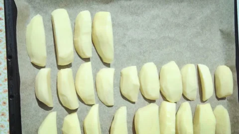 Close-up of a chef placing sliced potatoes on a baking sheet to bake in the oven Stock Footage 315269725