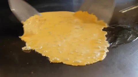 Close-Up of Chef Pouring Beaten Egg Batter onto a Hot Flat Top Griddle Stock-Footage 347688521