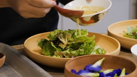 Close up of chef pouring dressing on salad in bowl in Malaysian restaurant Stock Footage 146544834