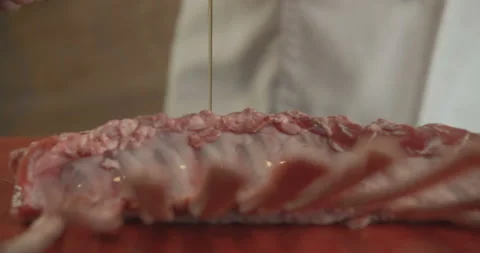 Close-up of chef pouring olive oil on fresh beef ribs. 4K slow motion video Stock Footage 103849156