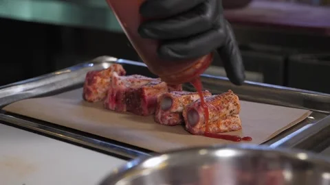Close-up of the chef pouring sauce over pork ribs before baking in the oven. Stock Footage 345131962