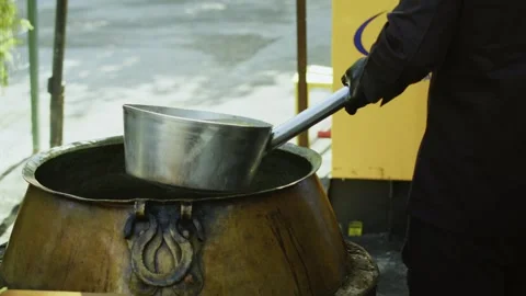 Close-up of chef pouring water from long-handled ladle into ancient kazan for Vidéo 332980332