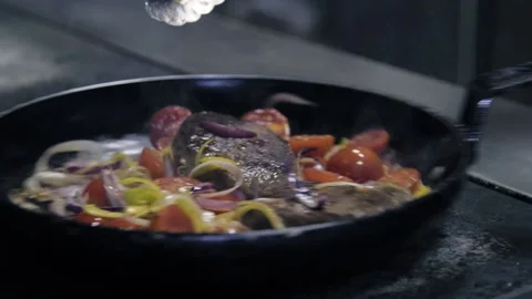 Close-up of the chef prepares meat and vegetables on a frying pan in the Stock Footage 146768475