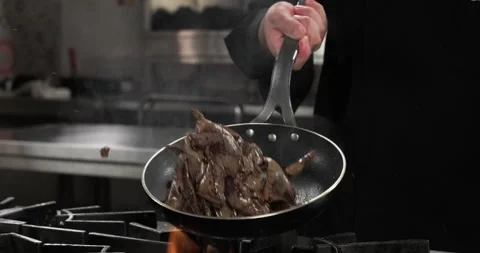 Close-up chef preparing beef liver in a frying pan on a gas stove, throwing in Stock Footage 294530126