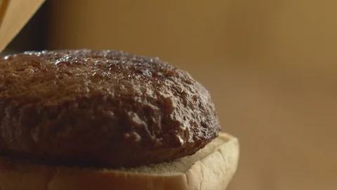 Close-up of chef preparing burger by adding slice of cheese to cutlet. Slow Stock Footage 116035834