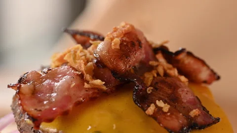 Close-up of a chef preparing a double hamburger. The chef sprinkles fried onions Stock Footage 296071302