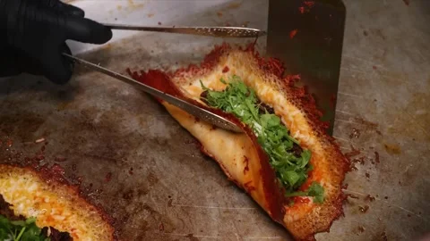 Close-up of Chef Preparing Gourmet Crispy Cheese Taco with Fresh Herbs on a Hot Stock Footage 331636982