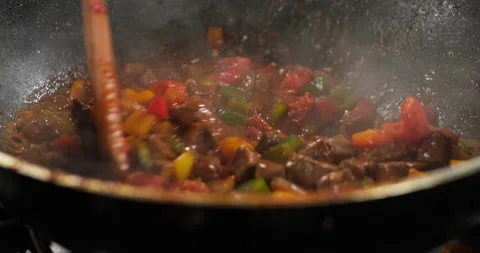 Close-up chef preparing meat and vegetables on a stove, stir meat colorful bell Stock Footage 290291818
