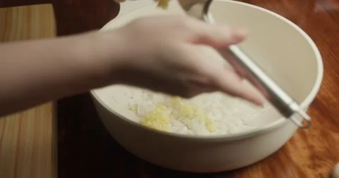 Close-up of a chef pressing fresh garlic into a white bowl with chopped onions Vídeo Stock 327687034
