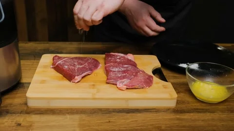 Close-up. The chef puts a beef steak on the board and salts Stock Footage 188540651