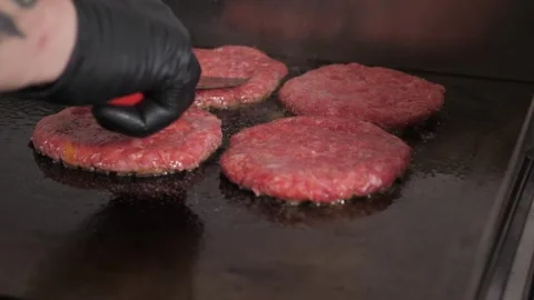 Close-up of the chef putting burger patties on an industrial oven in the kitchen Video stock 344038673