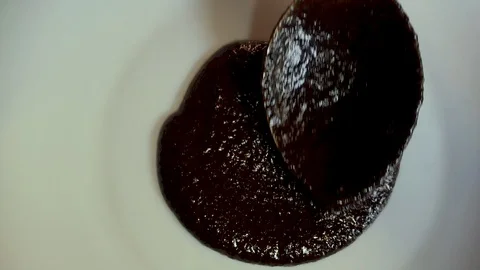 Close up of a chef putting dark mole sauce on a white plate with a spoon Stock Footage 123470978