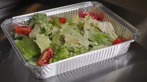 Close-up of a chef putting fried chicken in a Caesar salad on a disposable plate Video stock 344038725