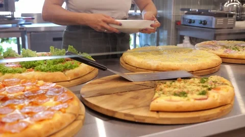 Close-up of a chef putting a slice of pizza in a triangular box in a restaurant. 스톡 동영상 319430831