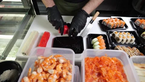 Close-up of a chef putting sliced sushi into a disposable plate in a restaurant. Stock Footage 323910515