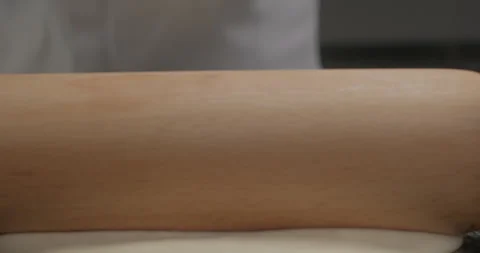 Close-up chef roll out dough with a rolling pin on a kitchen table, preparing Stock Footage 294247963