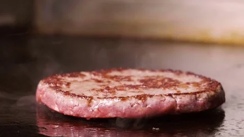 Close-up of chef salting one beef or pork cutlet frying on stove. Slow motion HD Stock Footage 84943763