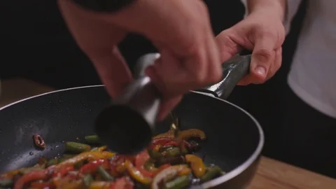 Close up of a chef sauteing vegetables and sausage in a pan in a kitchen, Stock Footage 82475107