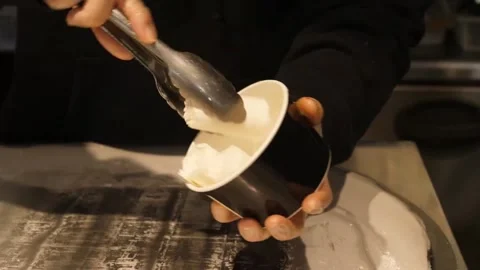 Close-up of Chef Scooping Fresh Ice Cream into a Black Paper Cup Stock-Footage 345293110