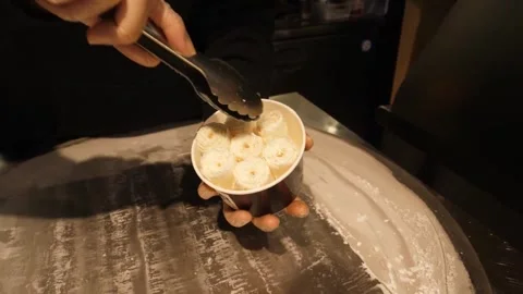 Close-Up of Chef Scooping Freshly Made Rolled Ice Cream into a Paper Cup Stock-Footage 345293188