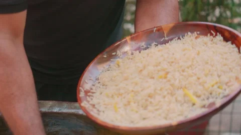 Close-up of chef serving Uzbek plov from cauldron into wooden tray Stock Footage 332980949