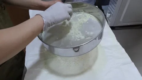 Close-up of Chef Sifting Flour or Powdered Ingredients Through a Metal Sieve in Video stock 345292486