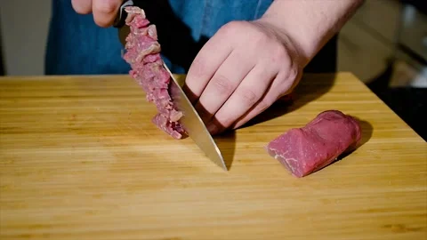 Close-up of a chef skillfully slicing raw meat on a cutting board. Stock Footage 194494015